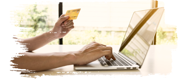 Person holding a yellow credit card and typing on a laptop, making an online purchase in a bright home setting