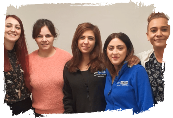 Group photo of five women from the EWI Store support team standing together and smiling, wearing branded clothing in front of a neutral background